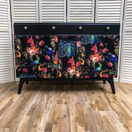 This upcycled sideboard has been completely stripped down, painted in black acrylic, decoupaged with a dark peacock and floral wallpaper with the finishing flourish of Anthropologie handles in turquoise and black.
